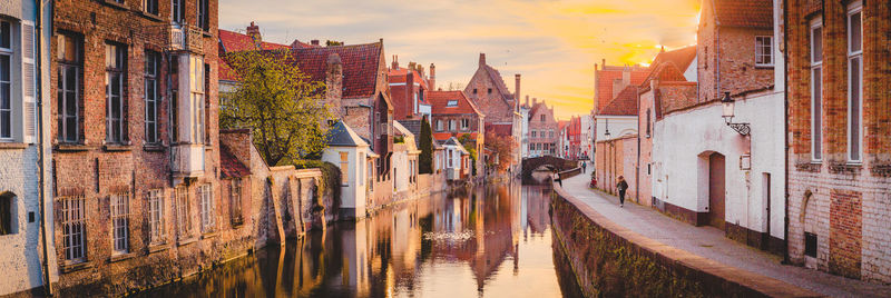 Panoramic view of canal amidst buildings in city during sunset
