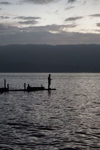 Silhouette people in sea against sky