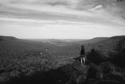 Rear view of man standing on mountain against sky