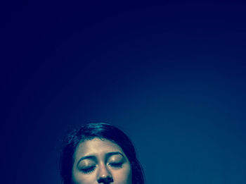 Portrait of young woman against blue background