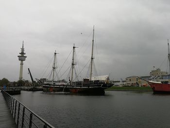 Sailboats moored at harbor against sky