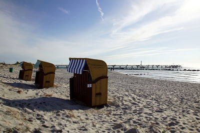 Hooded chairs on beach against sky