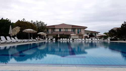 Swimming pool in building against cloudy sky