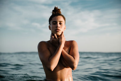 Portrait of shirtless young woman swimming in sea against sky