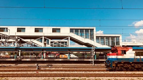 Train on railroad tracks by buildings against sky