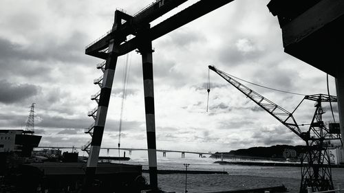 Low angle view of cranes at harbor