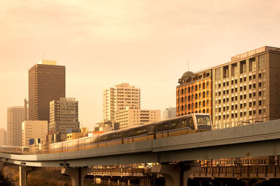 Low angle view of subway train moving in city during sunset