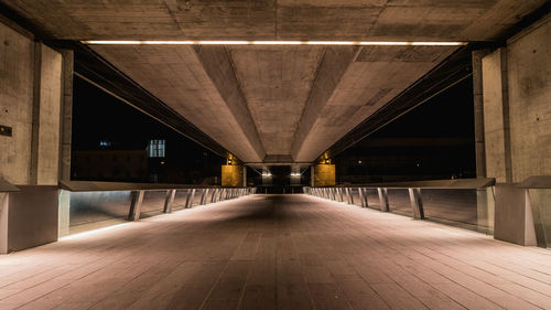 Empty corridor in illuminated built structure at night