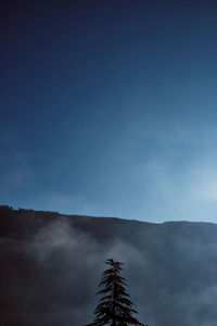 Low angle view of cross on mountain against sky