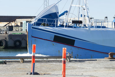 Ship moored at harbor against blue sky