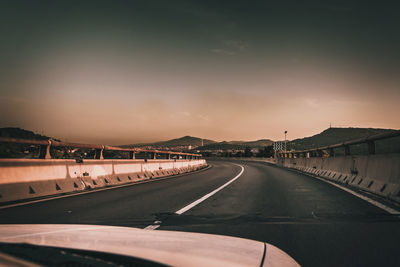 Road sen through car windshield against sky during sunset