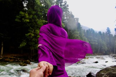 Rear view of woman holding hand at riverbank