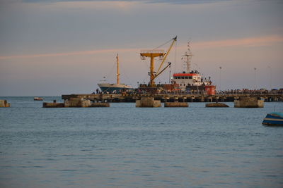 Commercial dock by sea against sky during sunset