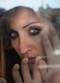 Close-up portrait of depressed woman seen through glass window