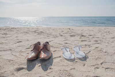 High angle view of shoes on sand at beach against sky