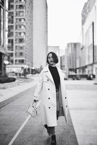 Portrait of young woman standing on street in city