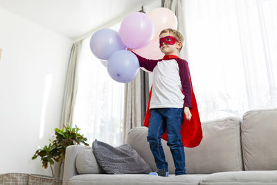 Rear view of woman with balloons on sofa at home