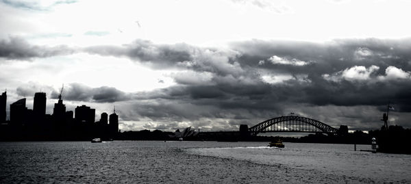 View of bridge and buildings against cloudy sky