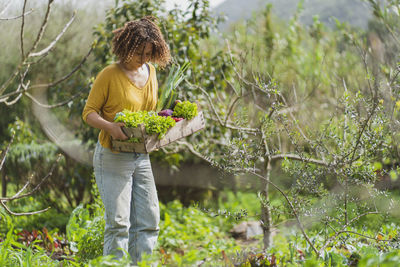 Woman holding plant on field