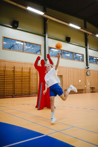Female handball player throwing ball in sports court