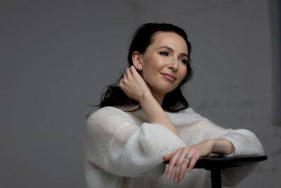 Portrait of young woman standing against wall