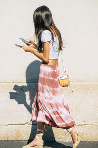 Full length of woman standing against wall