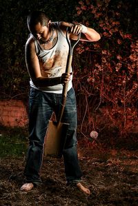 Young man with shovel working in yard at night