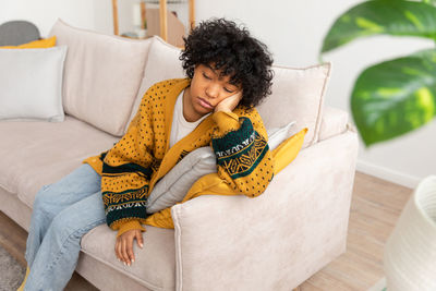 Young woman sitting on sofa at home