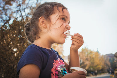 Close-up of girl having ice cream while standing outdoors