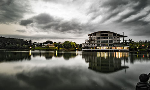 Reflection of building in lake against cloudy sky