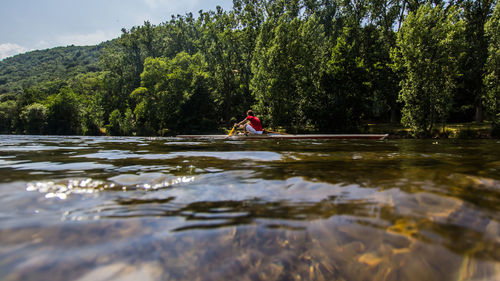 Man by river against trees