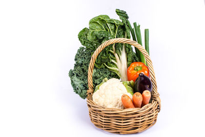 Close-up of vegetables in basket against white background