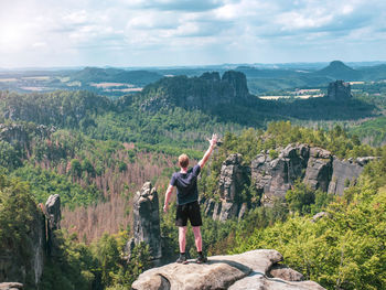 Hiker shouts to valley bellow carolafelsen rock, jagged mountains schrammsteine and falkenstein