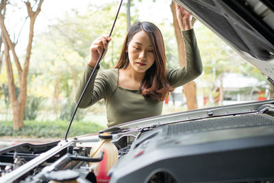 Angry asian woman and using mobile phone calling for assistance after a car breakdown on street.