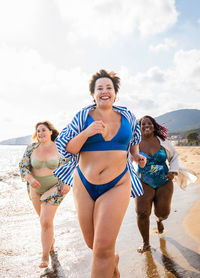 Portrait of woman in bikini standing at beach