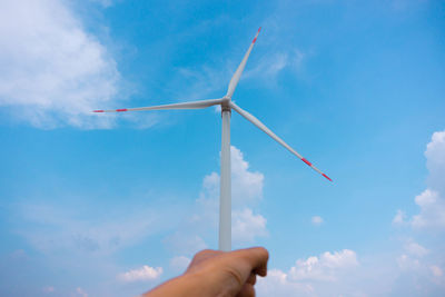Optical illusion of cropped hand holding windmill against sky
