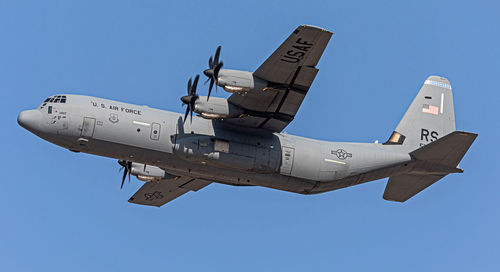 Low angle view of airplane flying against clear blue sky