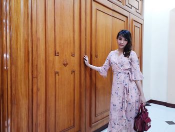 Portrait of woman standing by closet at home