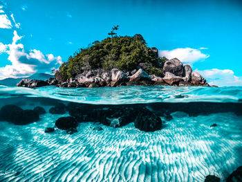 Surface level of rocks in sea against blue sky