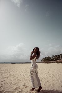 Woman standing on beach against sky