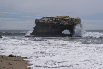 Rock formation on sea shore against sky