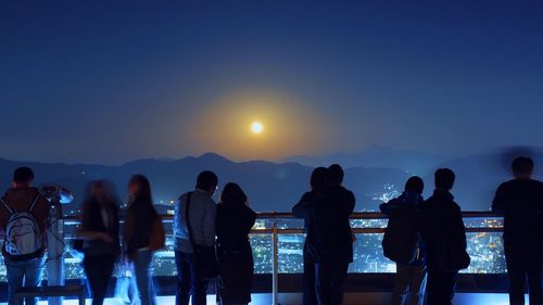 Silhouette people standing on building terrace against sky during dusk