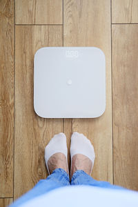 Woman in blue jeans weighing herself on floor scales