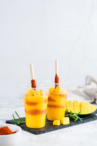 Mangonada drink made from mango and tajin chili powder in plastic glasses on the table. 