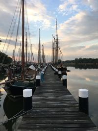 Sailboats moored at harbor against sky