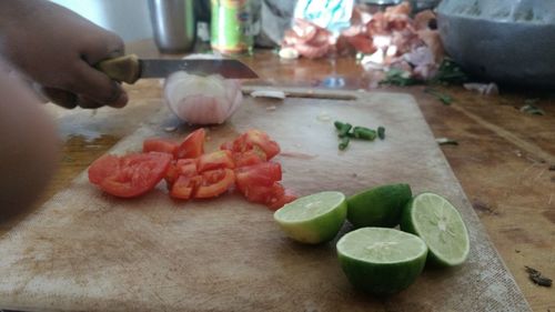 Close-up of hand holding vegetables on cutting board