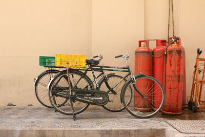 Bicycles by fire extinguisher on footpath by wall