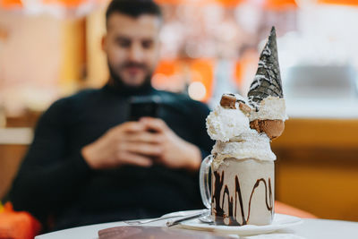 Midsection of person holding ice cream on table in restaurant