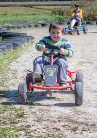 Little boy races others around a track on a peddle car at a fall festival