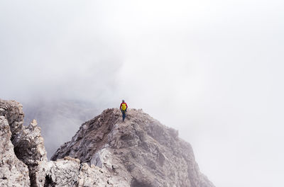 Rear view of person on rock in mountains against sky